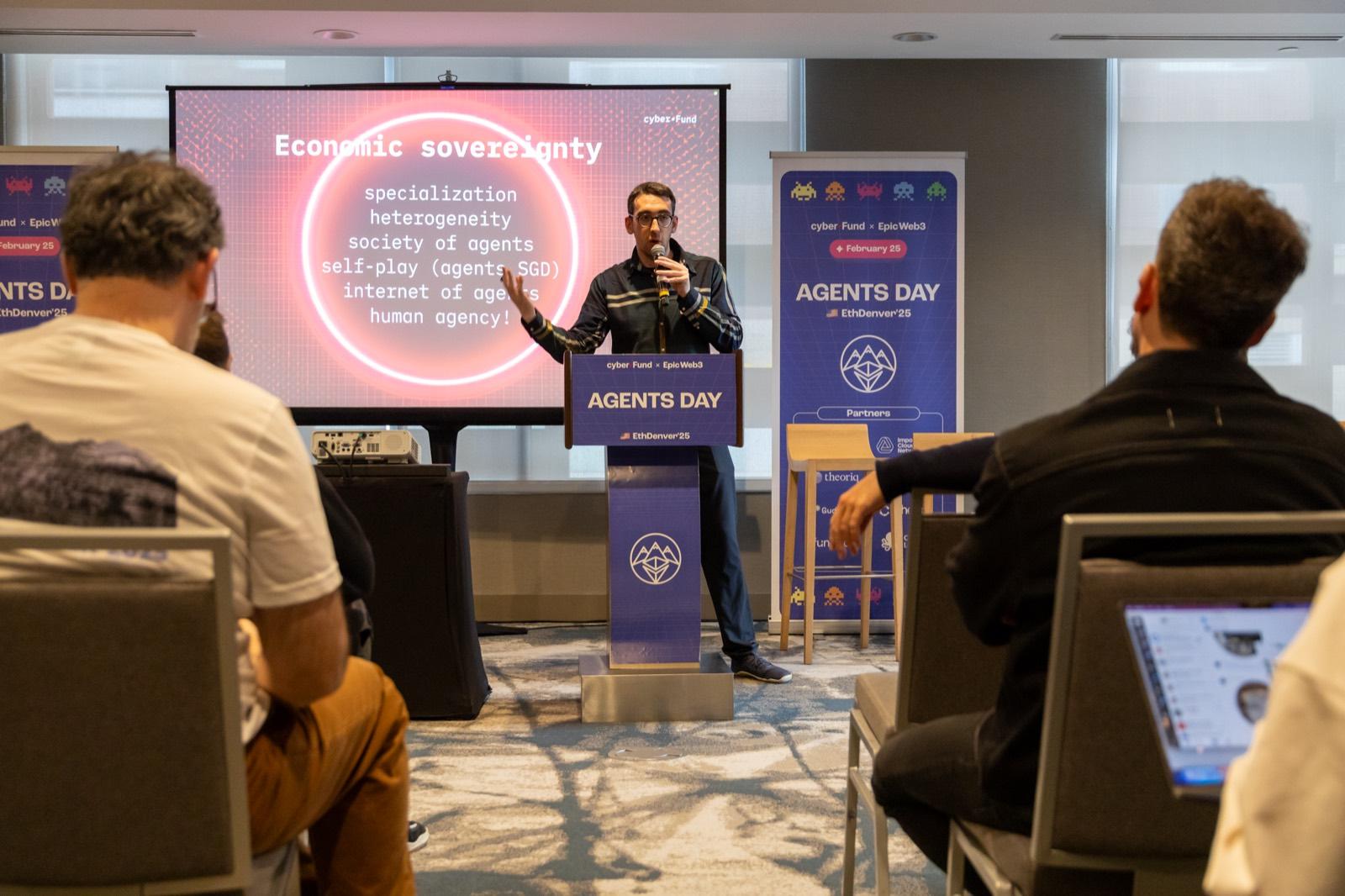 A speaker delivering a keynote from the podium at Agents Day