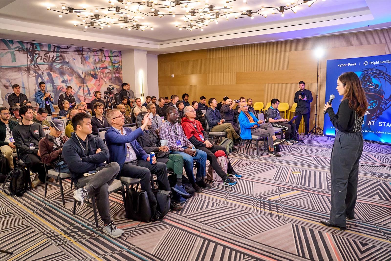 A speaker presenting in the round to a seated dAGI Summit audience
